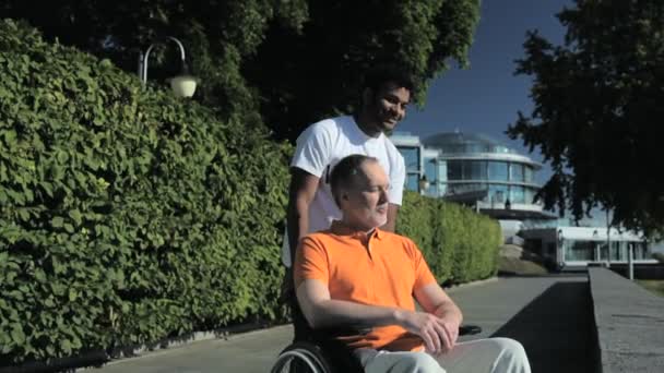 Voluntariado positivo cuidando de un hombre con silla de ruedas — Vídeo de stock