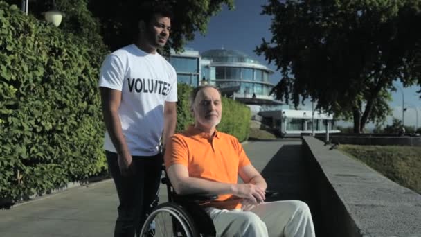 Voluntário hindu dedicado em pé no parque com um homem com rodas — Vídeo de Stock