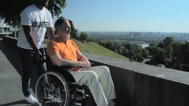 Volontario indù allegro che spinge un uomo sulla sedia a rotelle al punto di osservazione — Video Stock