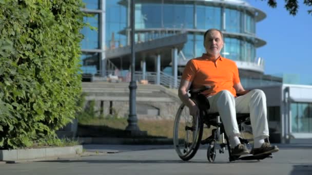 Приятный пожилой человек, сидящий в инвалидной коляске на улице — стоковое видео