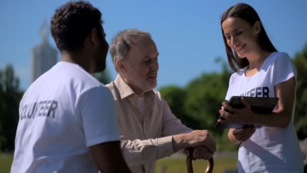 Voluntar tânăr bucuros folosind tabletă cu un bărbat în vârstă — Videoclip de stoc