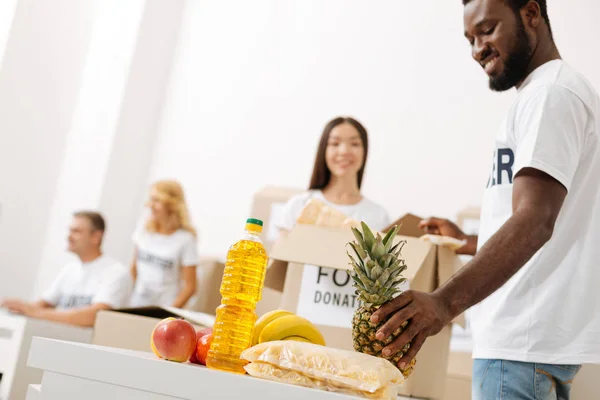 Jovens trabalhadores que embalam frutas e outros suprimentos — Fotografia de Stock