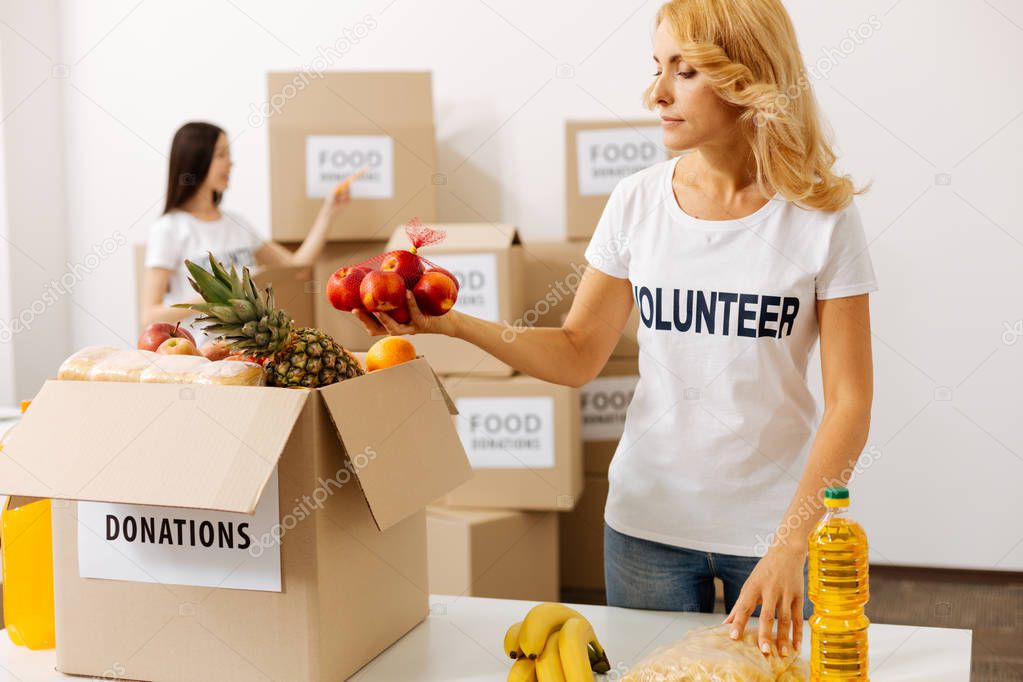 Energetic attentive woman packing fruits