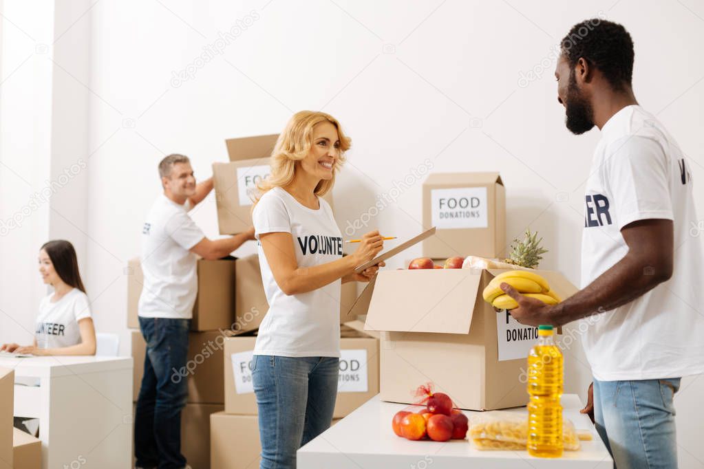 Devoted sincere woman helping her colleague compiling a parcel