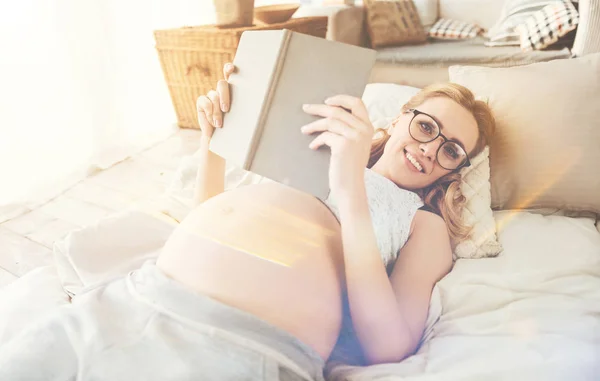 Радостная беременная женщина читает книгу — стоковое фото