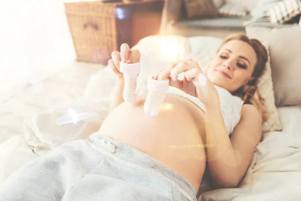 Pregnant woman holding clothes for her baby — Stock Photo, Image