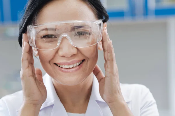 Encantada científica de laboratorio arreglando sus gafas protectoras —  Fotos de Stock