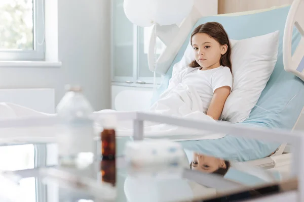 Menina sentada na cama e olhando para a medicina — Fotografia de Stock