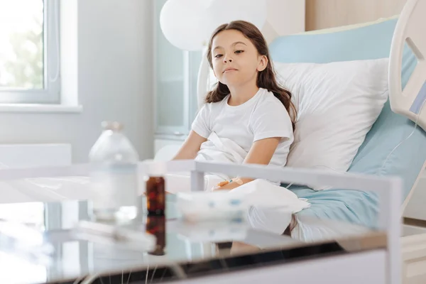 Dziewczyna siedzi na łóżku i patrząc na lek — Zdjęcie stockowe