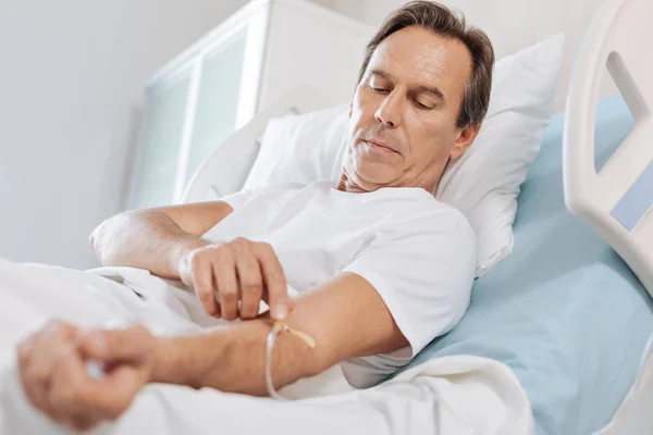 Un buen hombre serio tocando el catéter intravenoso — Foto de Stock