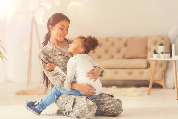 Mooi meisje zit in de schoot van haar moeder-soldaat — Stockfoto