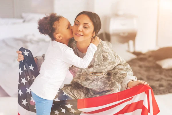 Hijita besando a su madre sosteniendo bandera de EE.UU. — Foto de Stock