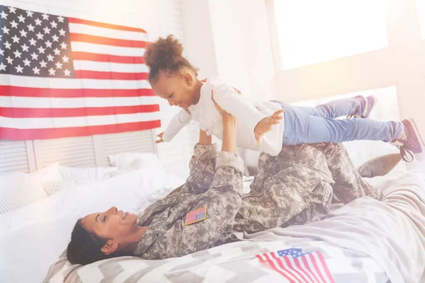 Mother lifting up her daughter as an airplane