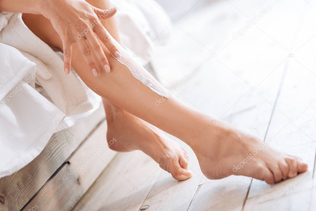 woman using lotion and massaging legs