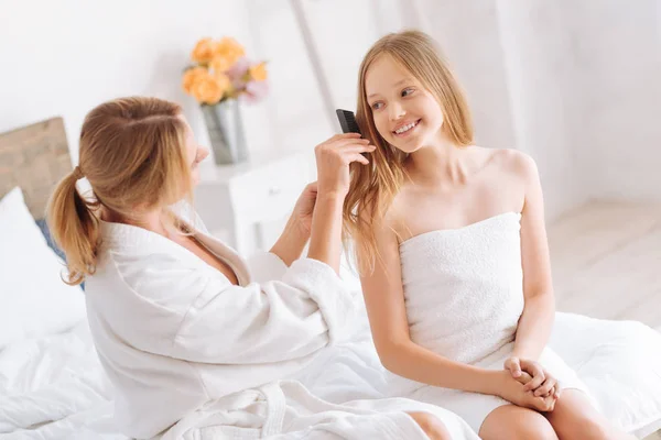 Mother brushing hair of cheerful daughter — Stock Photo, Image