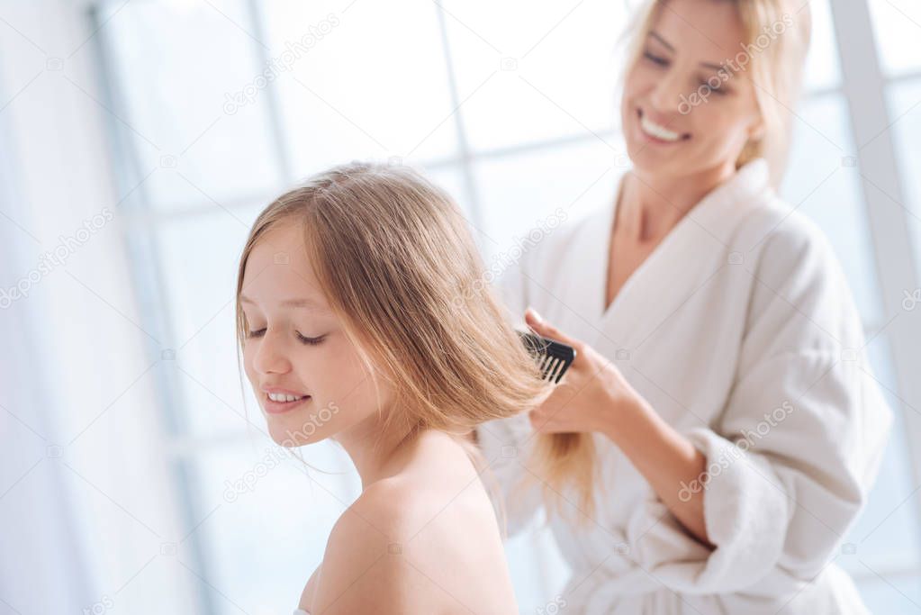 woman combing long hair of daughter