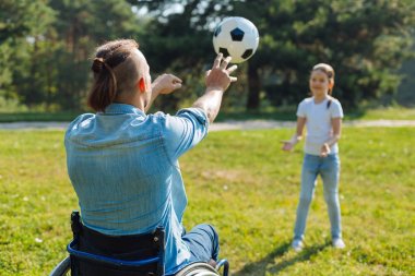 Genç adam kızı için bir top geçen tekerlekli sandalyede