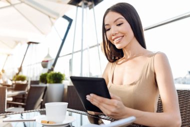 Bir tablet üzerinde çalışan neşeli pozitif kadın