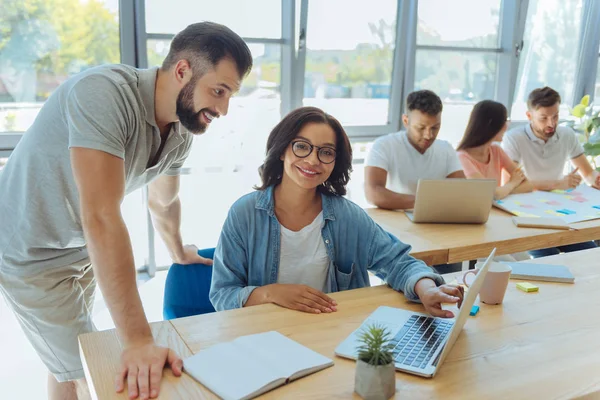 Mujer alegre inteligente que apunta a la pantalla del ordenador portátil — Foto de Stock