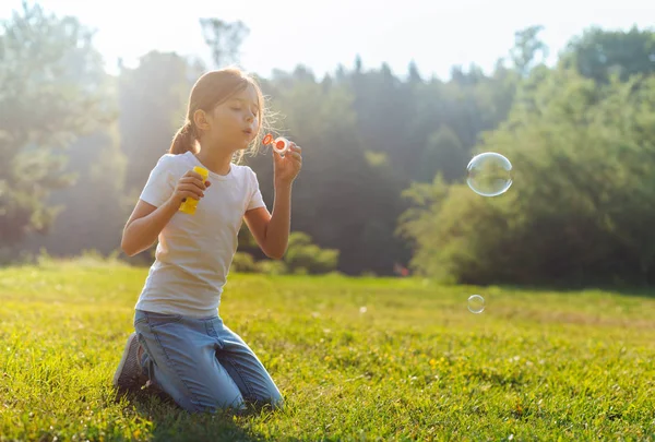 Meisje blazen van zeepbellen in de weide — Stockfoto