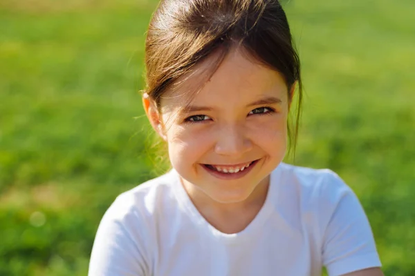 Portrait of smiling little girl against grassy background — Stock Photo, Image