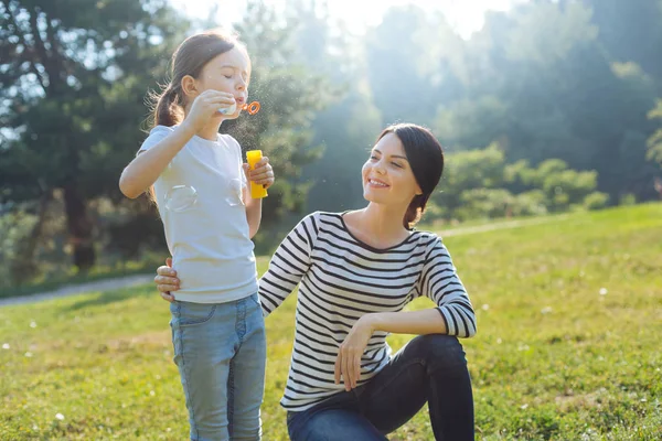 Charming mother watching her daughter blow bubbles — Stock Photo, Image