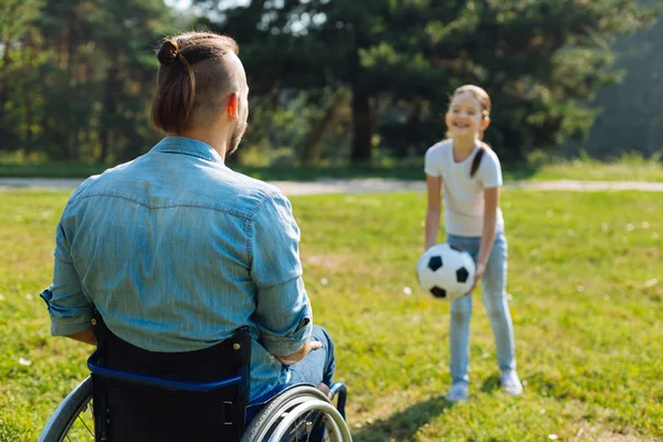 Joven en silla de ruedas jugando pelota con su hija —  Fotos de Stock