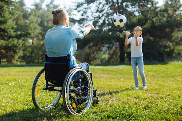 Man with disabilities playing volleyball with daughter