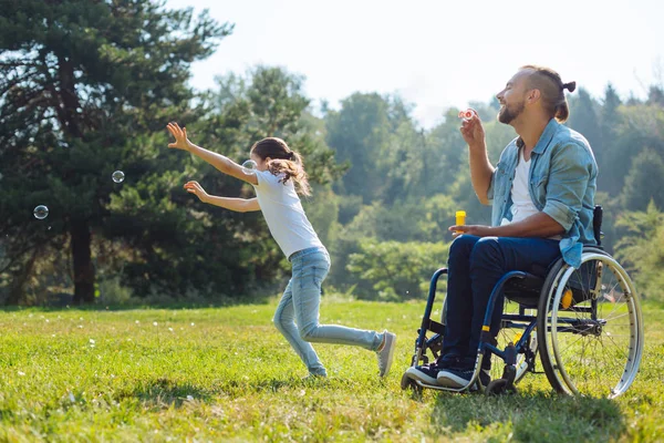 Joyeux père et fille handicapés jouant avec des bulles de savon — Photo