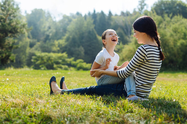 Cheerful daughter and mother laughing together outdoors