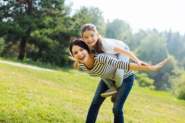 Mãe feliz dando um passeio de piggyback para sua filha — Fotografia de Stock