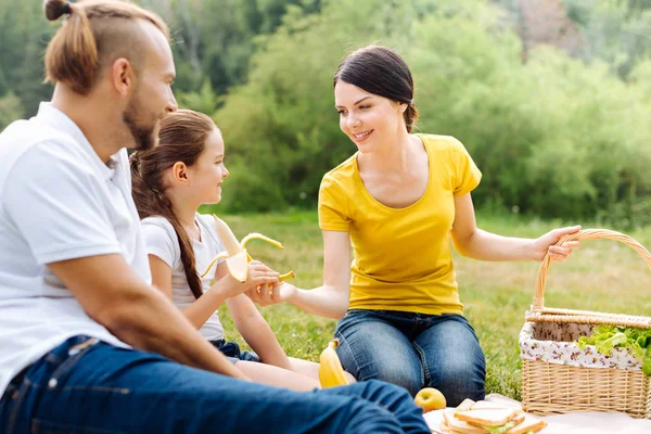 Cuidar de la madre dando un plátano a la hija en el picnic — Foto de Stock