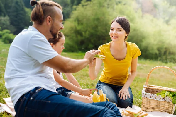 ครอบครัวหนุ่มสาวที่น่าพอใจ แบ่งปันอาหารในปิกนิก — ภาพถ่ายสต็อก