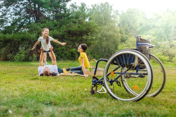 Joyeuse fille jouant avec son père handicapé couché sur l'herbe — Photo