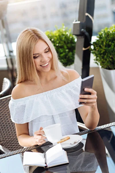Glad trevlig kvinna håller hennes smartphone — Stockfoto