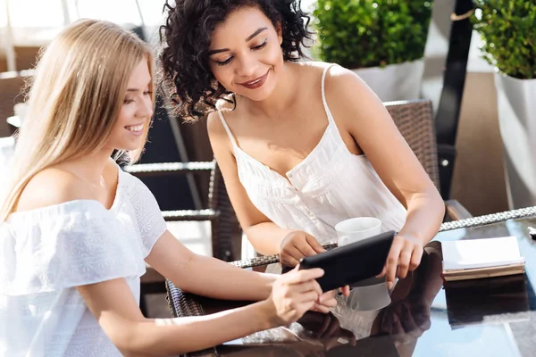 Mujer linda positiva mostrando una foto a su amigo — Foto de Stock