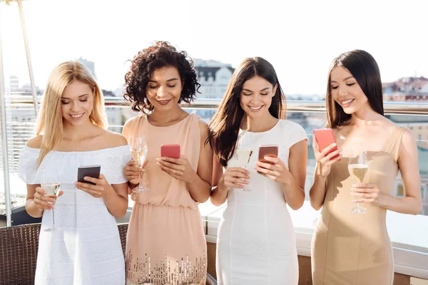 Mujeres jóvenes y alegres usando sus teléfonos inteligentes —  Fotos de Stock