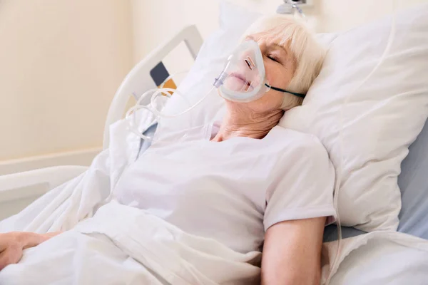 Unconscious elderly woman wearing an oxygen mask