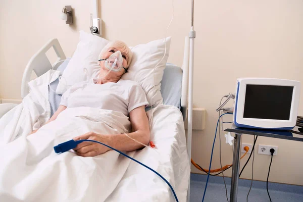 Senior sick woman recovering while wearing many medical devices — Stock Photo, Image