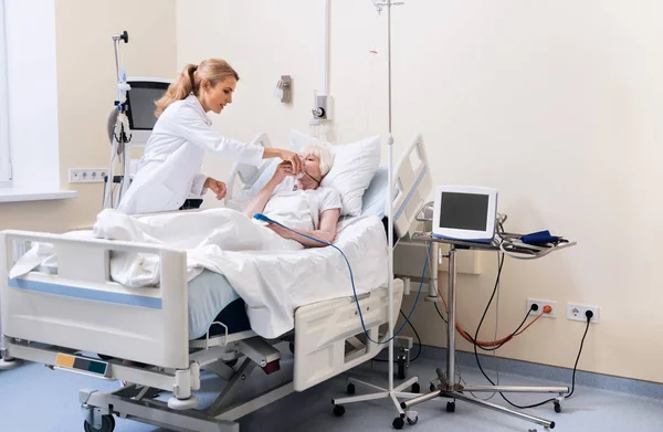 Bir maske bir hasta üzerinde koyarak nazik eğitimli doktor