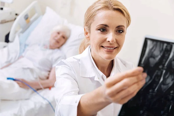 Intelligent trained doctor examining the scan of her elderly patient — Stock Photo, Image