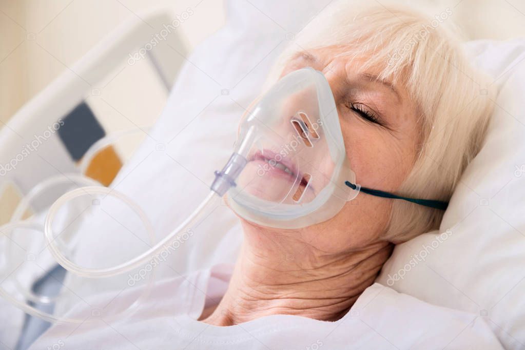 Pale unconscious lady breathing using special mask