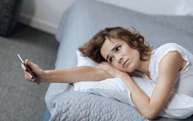 Onun akıllı telefon ekranına bakarak ponponsuz yorgun kadın