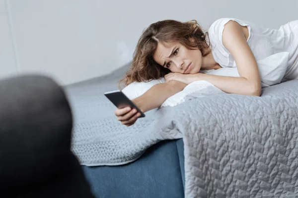 Mujer deprimida sin alegría estirando su mano con un teléfono inteligente —  Fotos de Stock