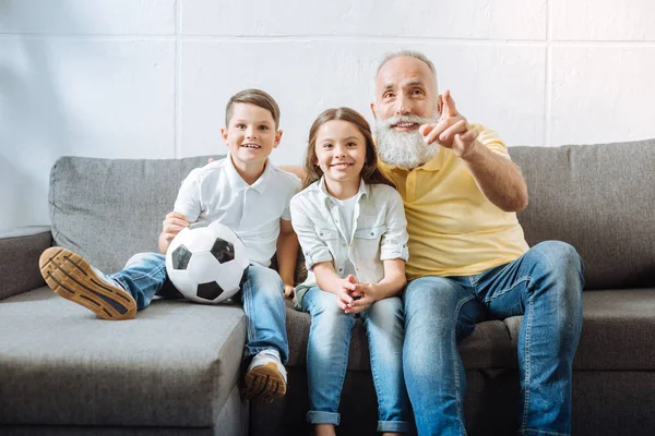 Farfar och hans barnbarn titta på höjdpunkterna i fotbollsmatch — Stockfoto
