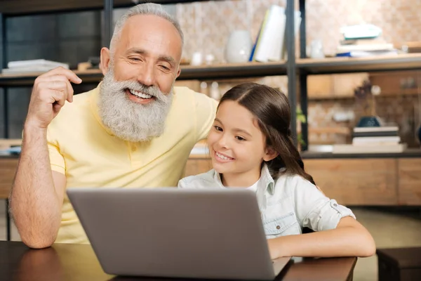 Encantador abuelo y nieta viendo vídeo en el ordenador portátil — Foto de Stock