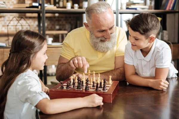 Abuelo sugiriendo a su nieto siguiente movimiento de ajedrez — Foto de Stock