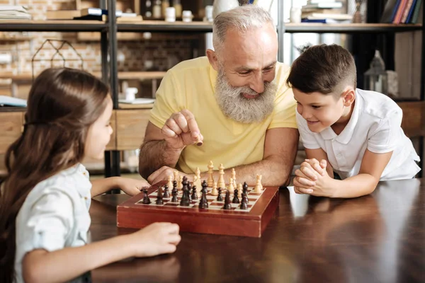 Дедушка показывает внукам, как играть в шахматы. — стоковое фото