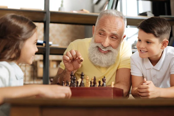Abuelo explicando reglas de ajedrez a sus nietos — Foto de Stock