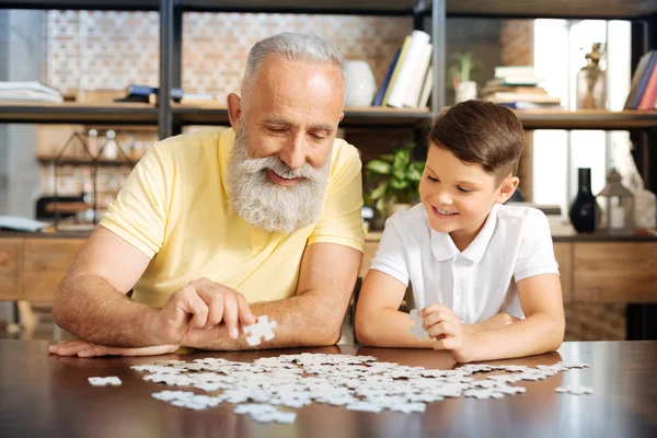 Smiling grandfather and grandson doing a jigsaw puzzle together — Stock Photo, Image